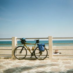 Bicycle parked by a beach railing under a clear sky